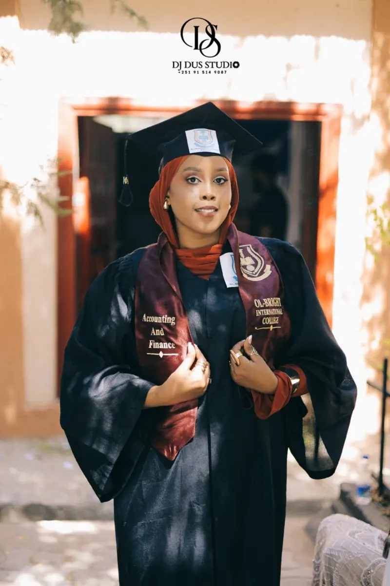A woman graduate poses with her graduation cap